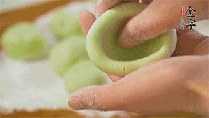 將均分的艾草面團搓成圓，挖一個窩，放入餡心，再搓成圓。