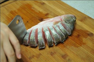 將鱸魚(yú)清洗干凈，從脊椎處切斷至腹部，腹部保留1cm左右不要切斷。