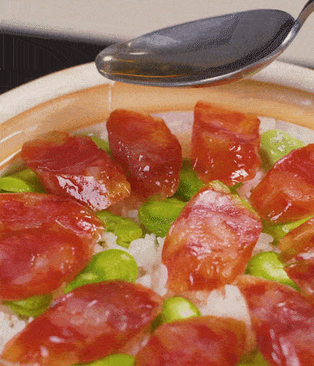 大米出現(xiàn)小孔時(shí)開(kāi)蓋放香腸，往鍋邊淋入少許油，再燜煮8~10分鐘左右。