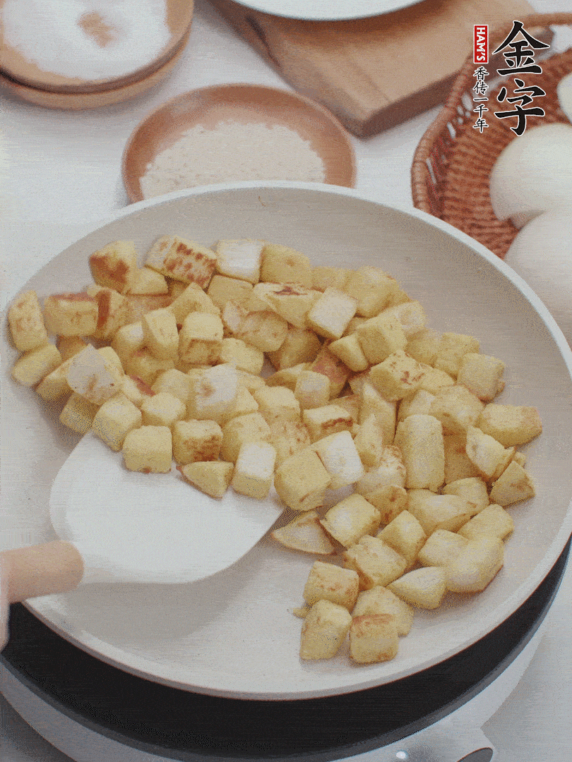 起鍋熱油，倒入饅頭丁，小火煎至蛋液凝固定型再翻面，饅頭丁部煎至金黃時(shí)盛起待用。