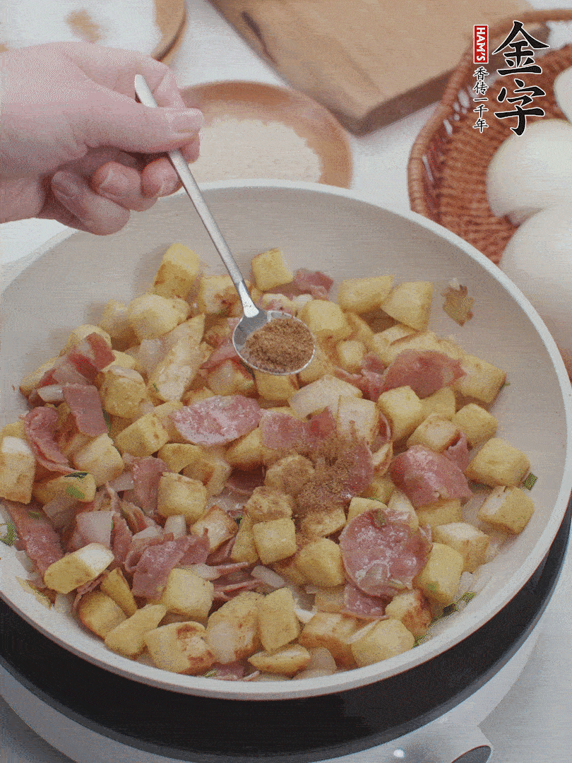 起鍋少油，煸香洋蔥丁、蔥白，加入金字培根火腿翻炒幾下，再加入饅頭丁、1小勺孜然粉、少許鹽翻炒均勻并鋪平。